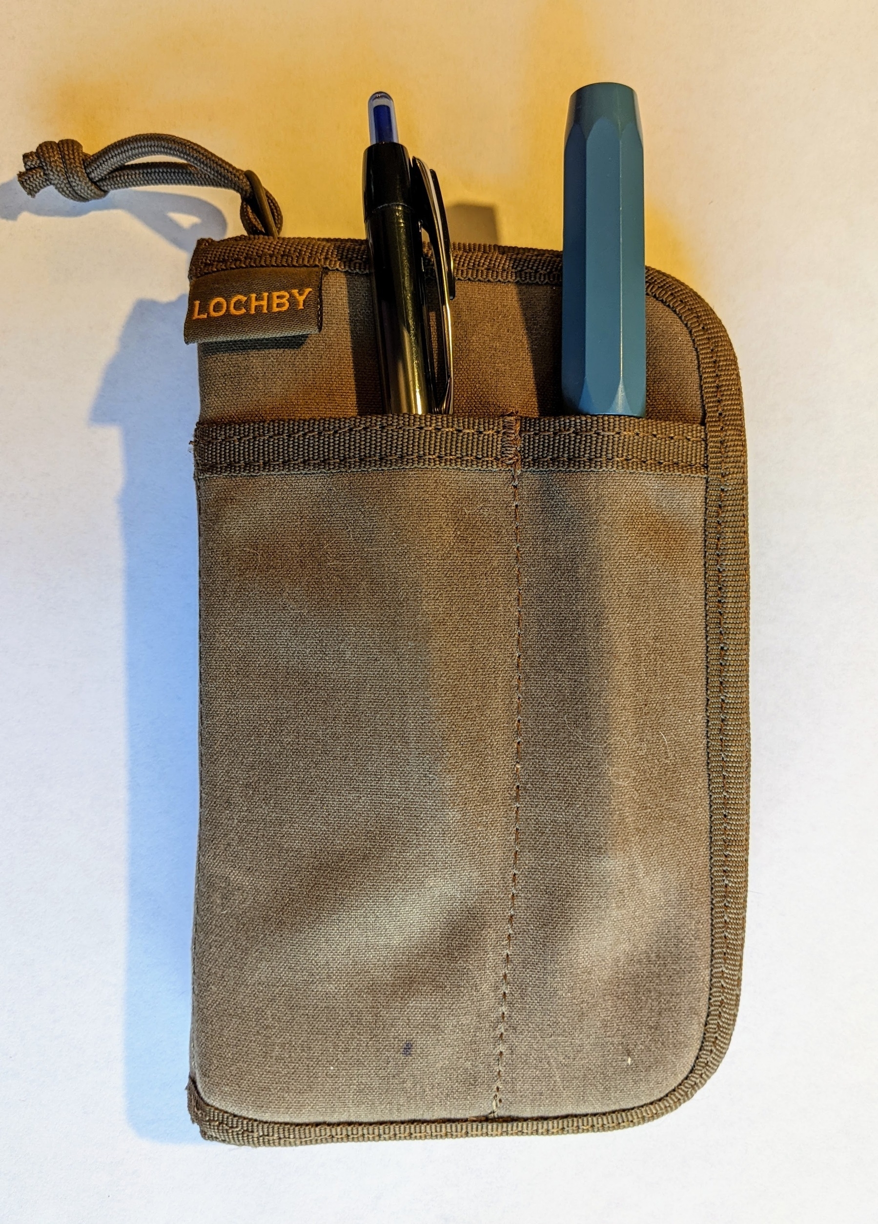 a travel notebook cover that zips shut, with pockets for pens on the outside