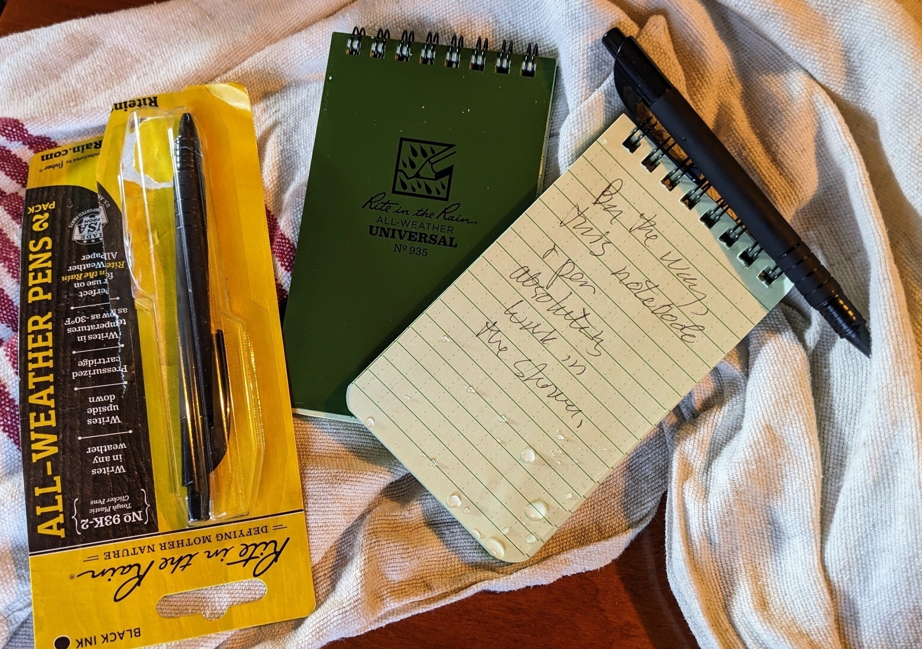 all-weather pocket notebook and pen, with water drops on them